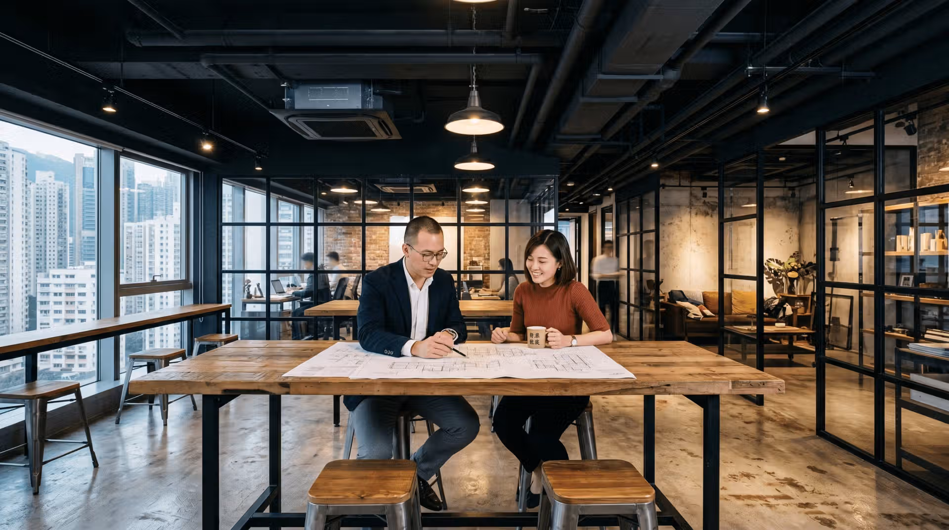 style_2_industrial_chic_1 專業人士正在討論辦公室翻新工程嘅平面圖,背景為開揚嘅甲級寫字樓景觀,體現專業嘅工作空間規劃流程。