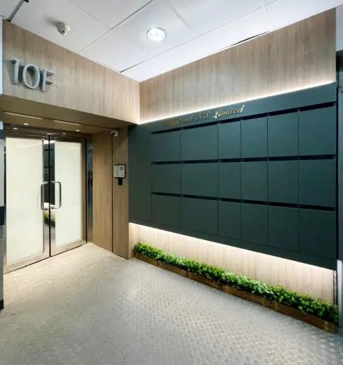 香港辦公室裝修工程：荔枝角商務中心大堂入口設計，定製深綠色霧面信箱牆飾面結合上下兩側 LED 隱藏式線性燈帶照明與高質感木紋木工飾板